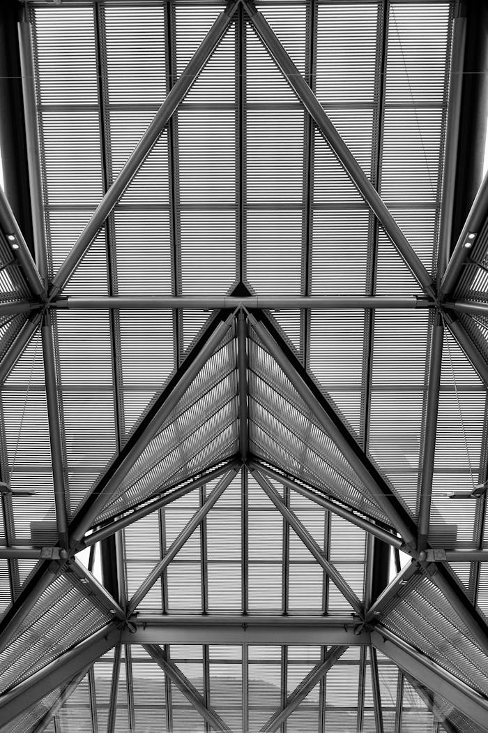 Black and white geometric ceiling structure with metal beams forming triangle patterns.